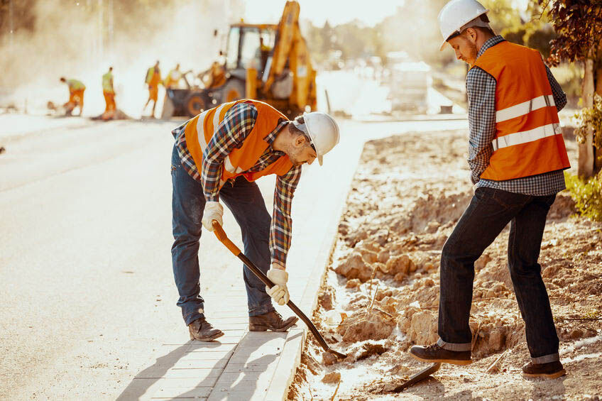 Workers in reflective vests using shovels during carriageway wor